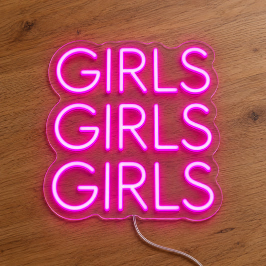 Girls LED Neon Sign in pink, featuring three stacked words on a wooden surface.