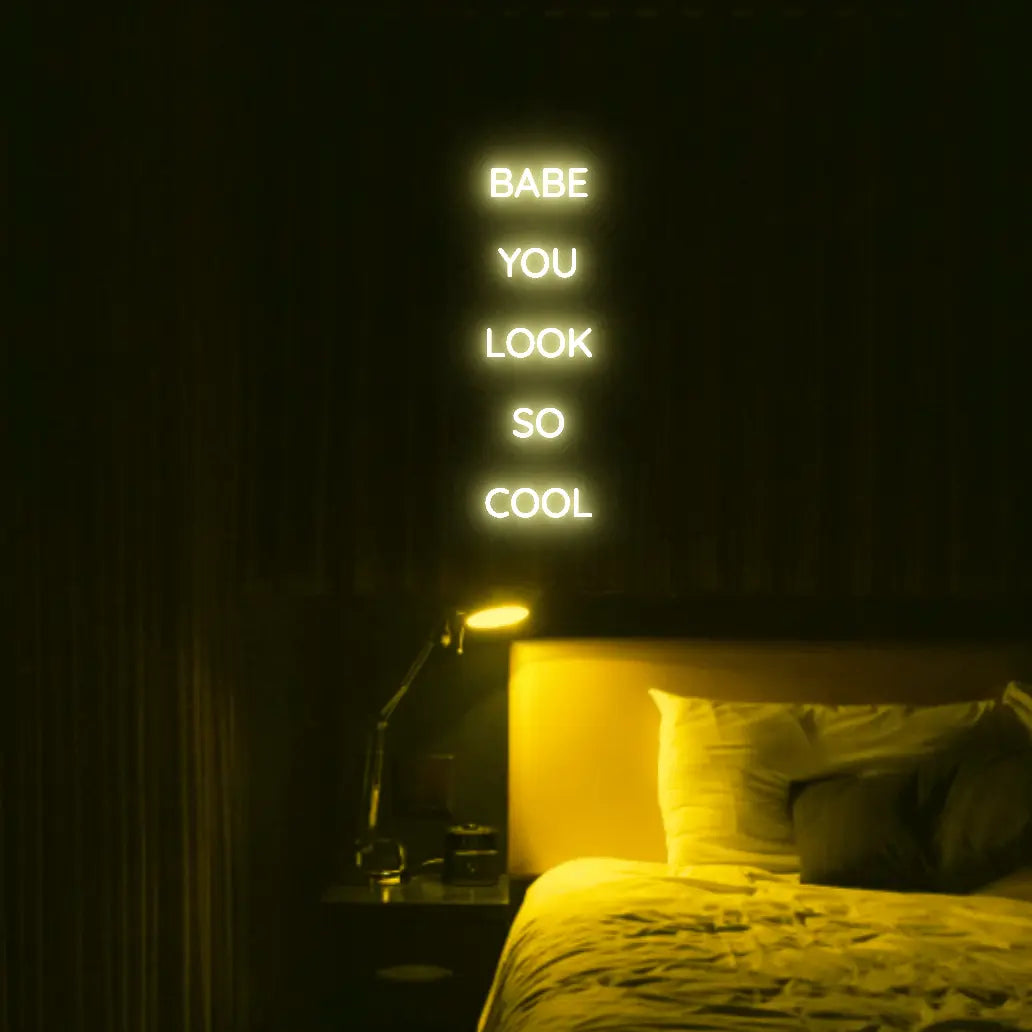 Babe You Look So Cool 2 LED Neon Light Sign in yellow, featuring five stacked words illuminated above a bed.