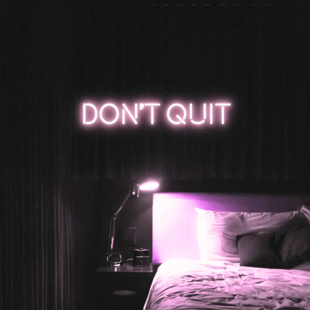 Don't Quit LED Neon Light Sign in pale pink, featuring block lettering illuminated above a bed.