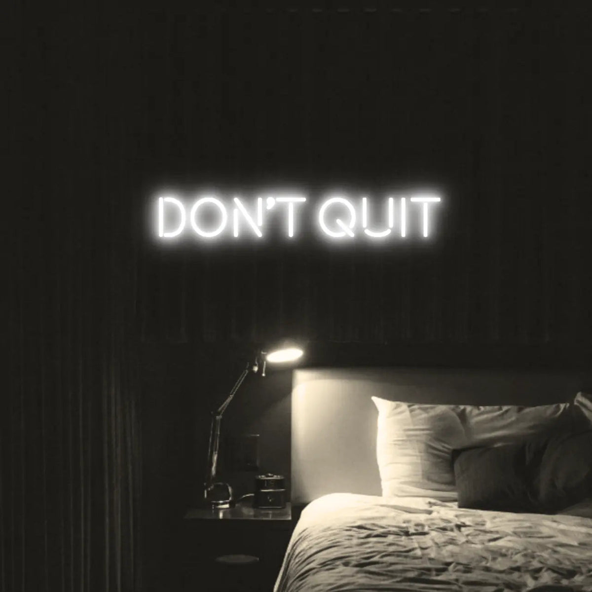 Don't Quit LED Neon Light Sign in white, featuring block lettering illuminated above a bed.