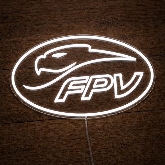 An oval LED neon-style sign with a white outline and the letters FPV, featuring a bird head graphic above the text, placed on a dark wood surface.