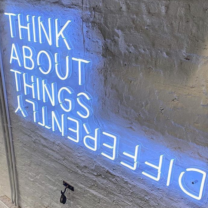 Ice Blue Neon sign saying "think about things differently" on a white wall in Australia Office