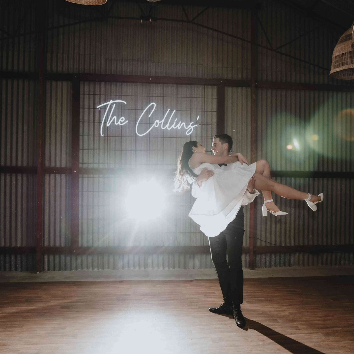 Man lifting a woman in a dance pose with 'The Collins' text in the background at Perth Wedding