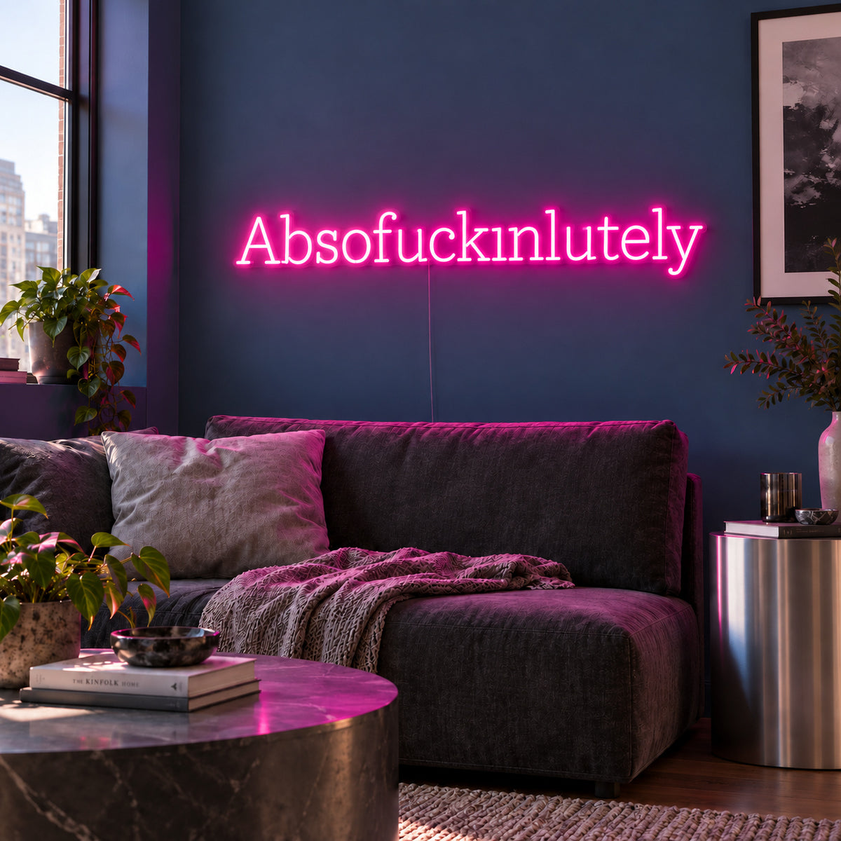 Rose Red version of the Absofuckinlutely Neon Sign, shown above a charcoal sofa on a blue wall.
