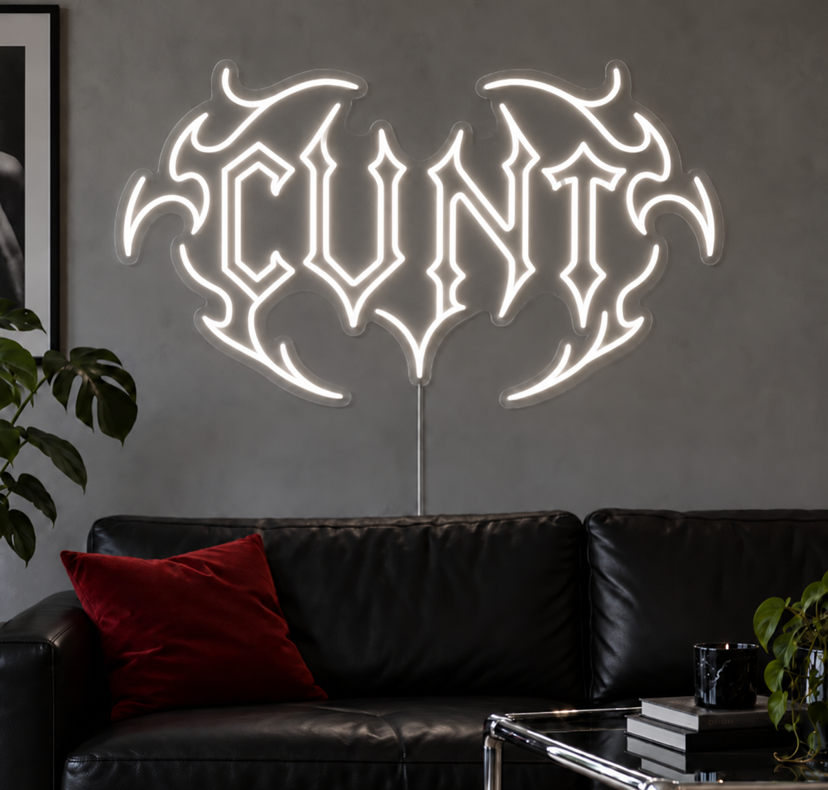 Cunt Neon Sign in White LED neon with double outlined C, displayed above a black leather sofa.