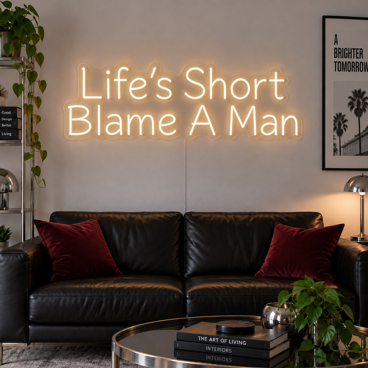 Warm White version of the Life's Short Blame A Man Neon Sign, shown above a black leather sofa.