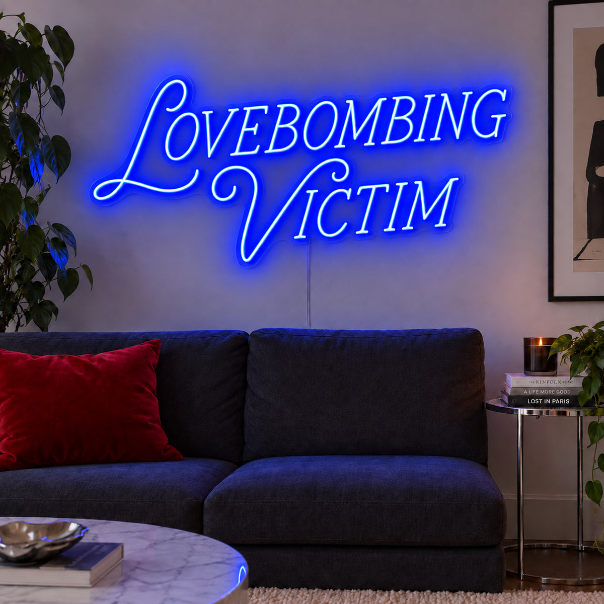 Lovebombing Victim Neon Sign glowing blue above a dark sofa with red cushions.