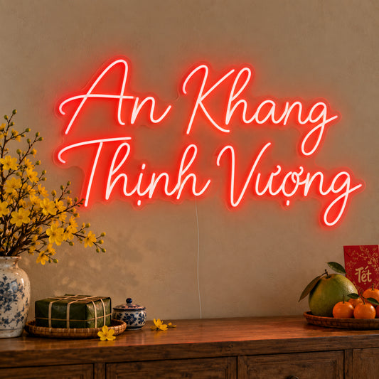 An Khang Thịnh Vượng Neon Sign on clear cut-to-shape acrylic, illuminated on a wall in a styled celebration setting