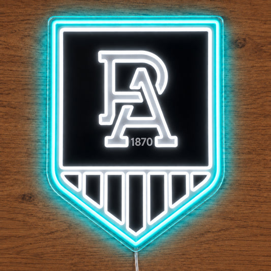 Port Adelaide Power neon sign glowing brightly on a wooden surface in dim lighting