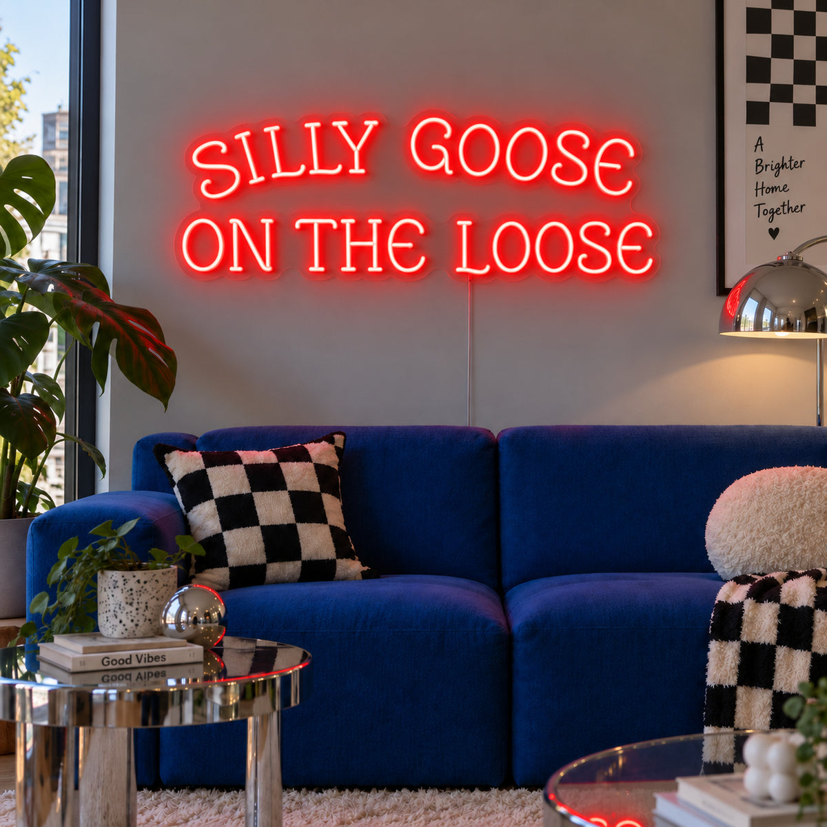 Silly Goose On The Loose Neon Sign with red lighting, displayed above a blue sofa with checkered cushions.